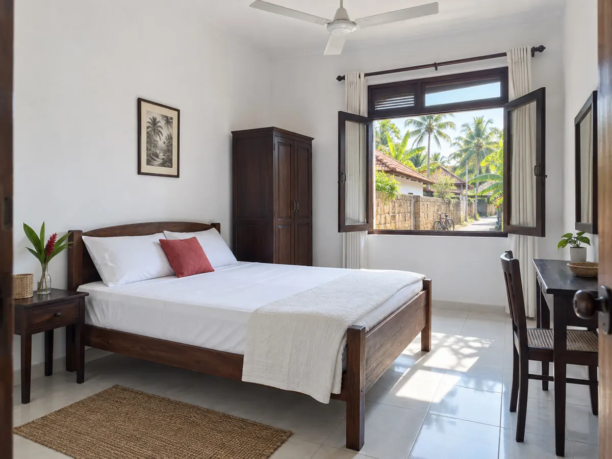Simple Hikkaduwa guest-house bedroom with tiled floor, a ceiling fan and morning light from the street side